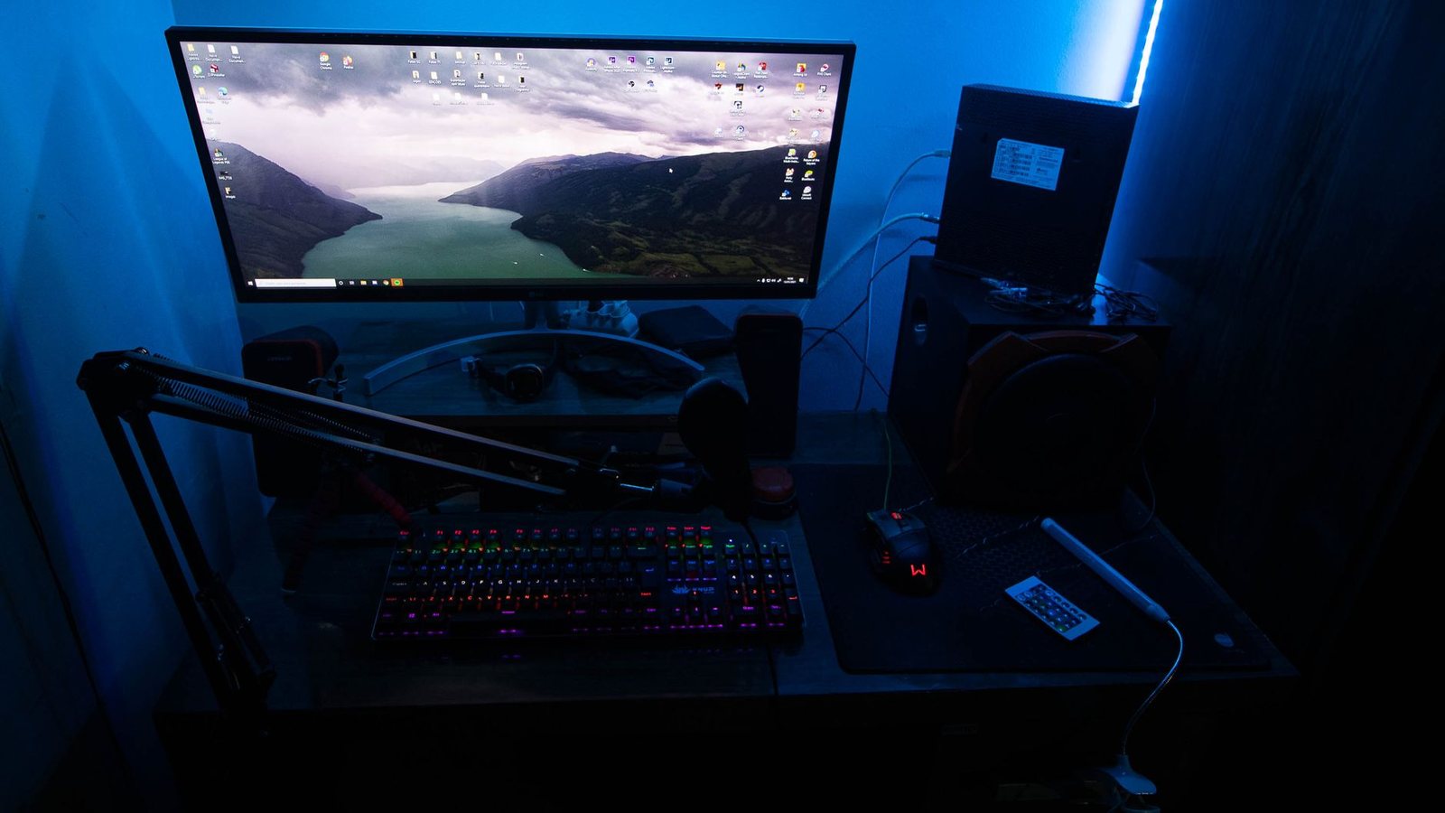 PC gaming desk with ultrawide monitor in a blue-lit room